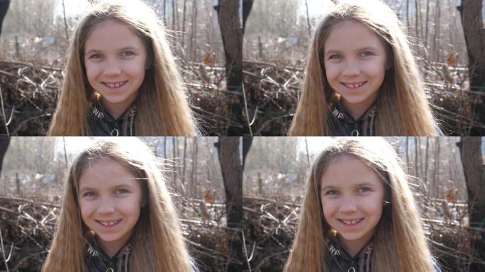 早春森林模糊背景下快乐可爱的小孩的肖像。美丽的微笑女孩看着户外的相机。关闭她脸上的女性孩子的积极情绪