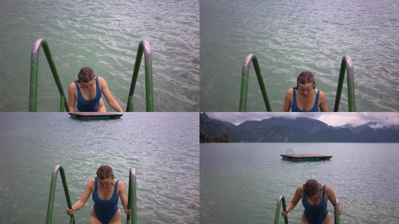 穿着蓝色泳衣的女人游泳后从湖上楼梯