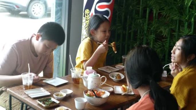 快乐的亚洲儿童在午餐时间/生活方式概念一起在餐厅吃日本食物。