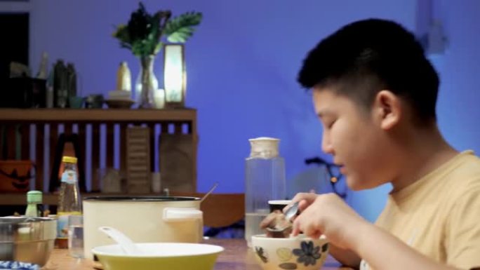 快乐的亚洲儿童晚上在家一起吃火锅sha锅或Sukiyaki，带led灯，生活理念。