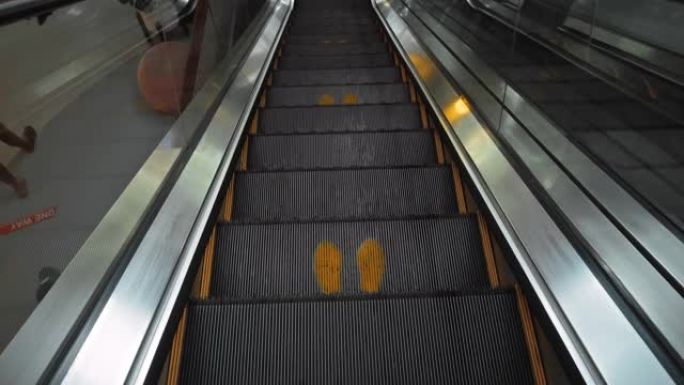 购物中心的楼梯escolator带有脚印标志，可保持社交距离