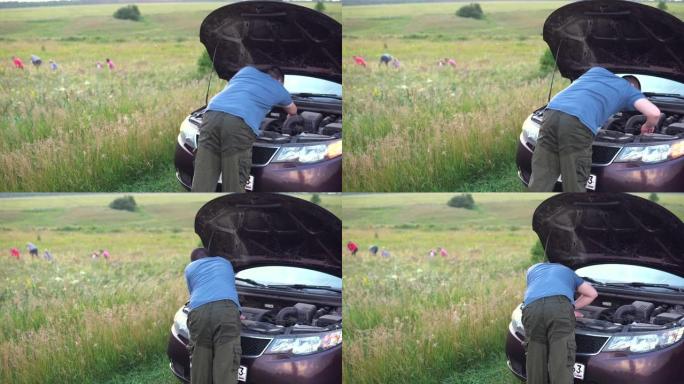 一家人在田野里散步时，一名男子检查汽车发动机。汽车故障