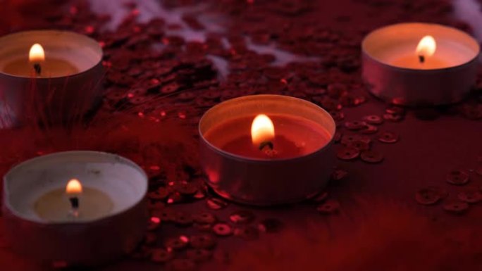 红色背景上燃烧的茶灯蜡烛的特写。浪漫的气氛与香薰茶轻蜡烛。情人节背景