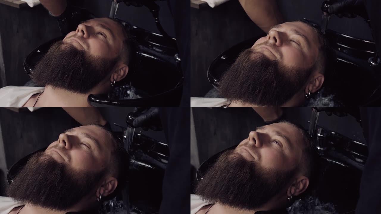 理发师在理发店里给一位大胡子顾客洗头。