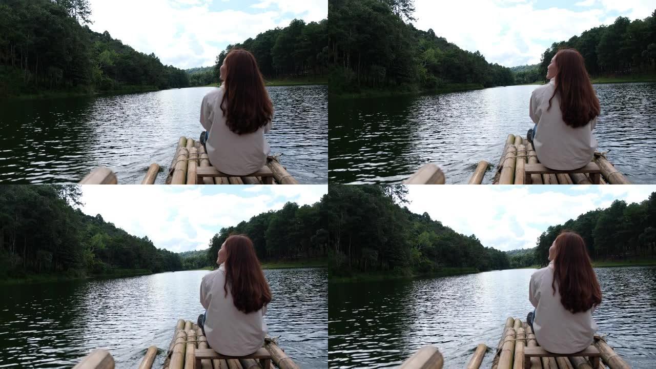 一位女性旅行者在湖中坐着和骑竹筏的后视图