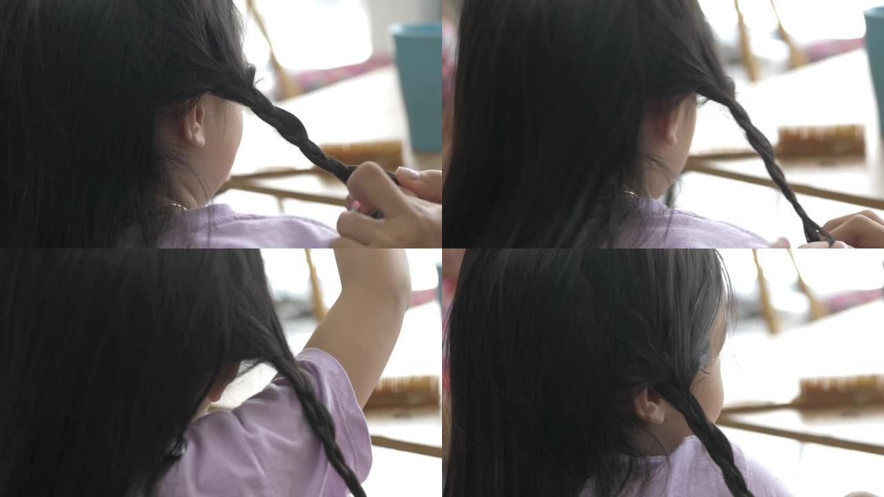 手亚洲女孩在家里编织姐姐头发，孩子们在一起玩得开心，生活方式理念。