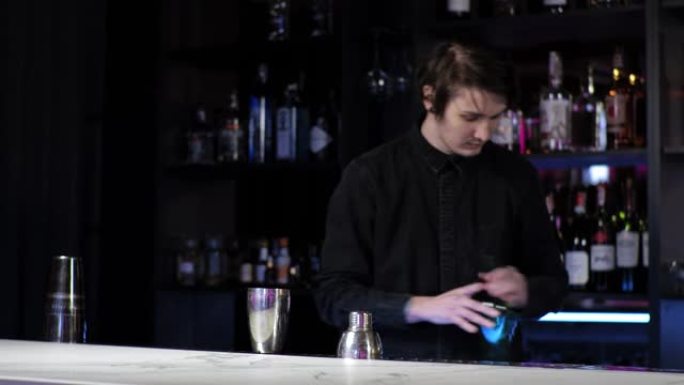 年轻的新手调酒师实习生准备鸡尾酒粗心的家伙在摇床中混合饮料和冰