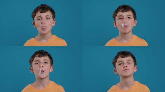 快乐的男孩嚼口香糖，学习膨胀气泡并使气泡破裂，快乐地微笑着看着蓝色背景上的相机慢动作。孩子。童年。人