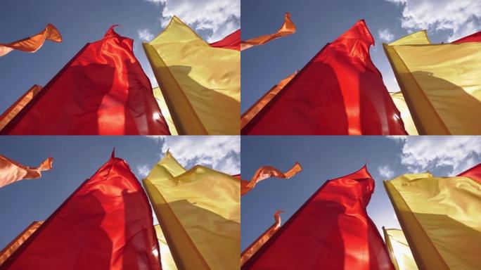 在晴朗的天空背景下以慢动作从下方拍摄的挥舞着节日旗帜的特写镜头