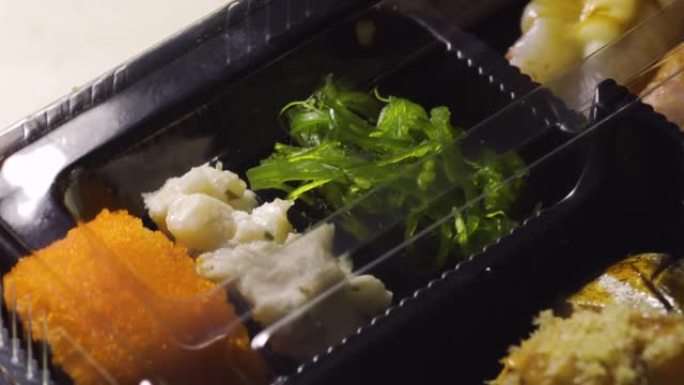 塑料包装的寿司种类繁多。在转盘上旋转。含有大量海鲜成分的日本食物。海藻。鳗鱼。虾。猪肉。米饭。和其他