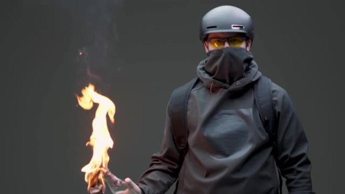 盖伊抗议者激进分子在黑色面具和头盔与火焰燃烧弹叛乱在灰色工作室背景