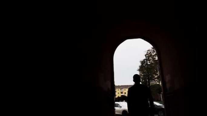 一名男子走进一栋住宅楼的椭圆形拱门。