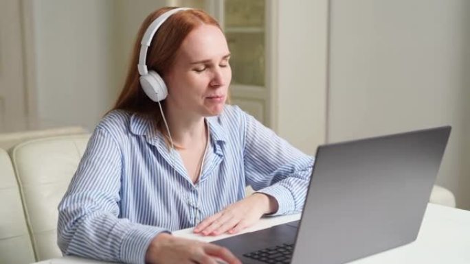 戴着耳机的女人在家在笔记本电脑上工作，主持课程或网络研讨会。