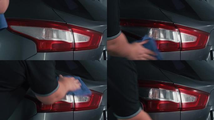 专业的汽车美容师在前灯上喷洒润滑剂清洁剂并用抹布擦拭，为汽车表面抛光做好准备