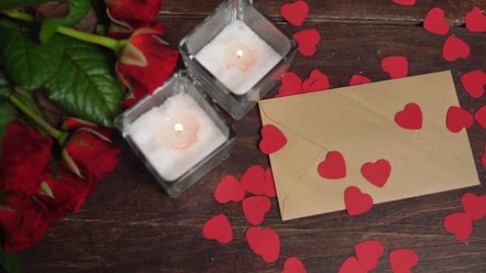 情人节浪漫背景 -- 红玫瑰、蜡烛和心。一只手拿起树上的工艺信封。