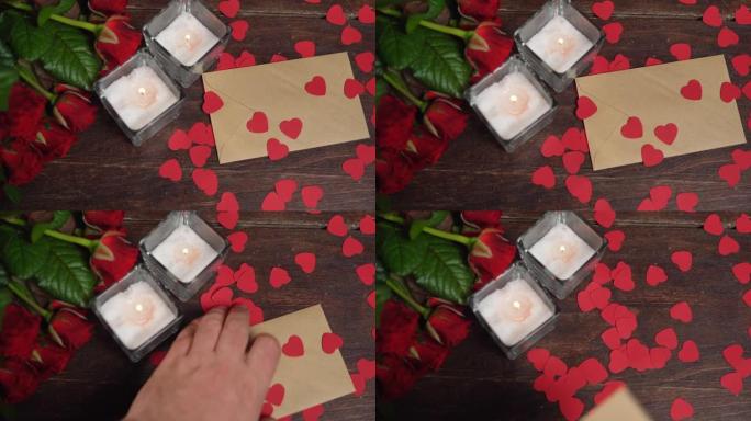 情人节浪漫背景 -- 红玫瑰、蜡烛和心。一只手拿起树上的工艺信封。