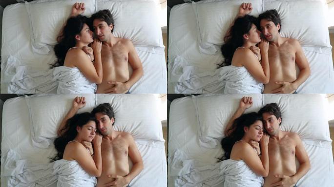 年轻夫妇躺在床上醒来，俯视图