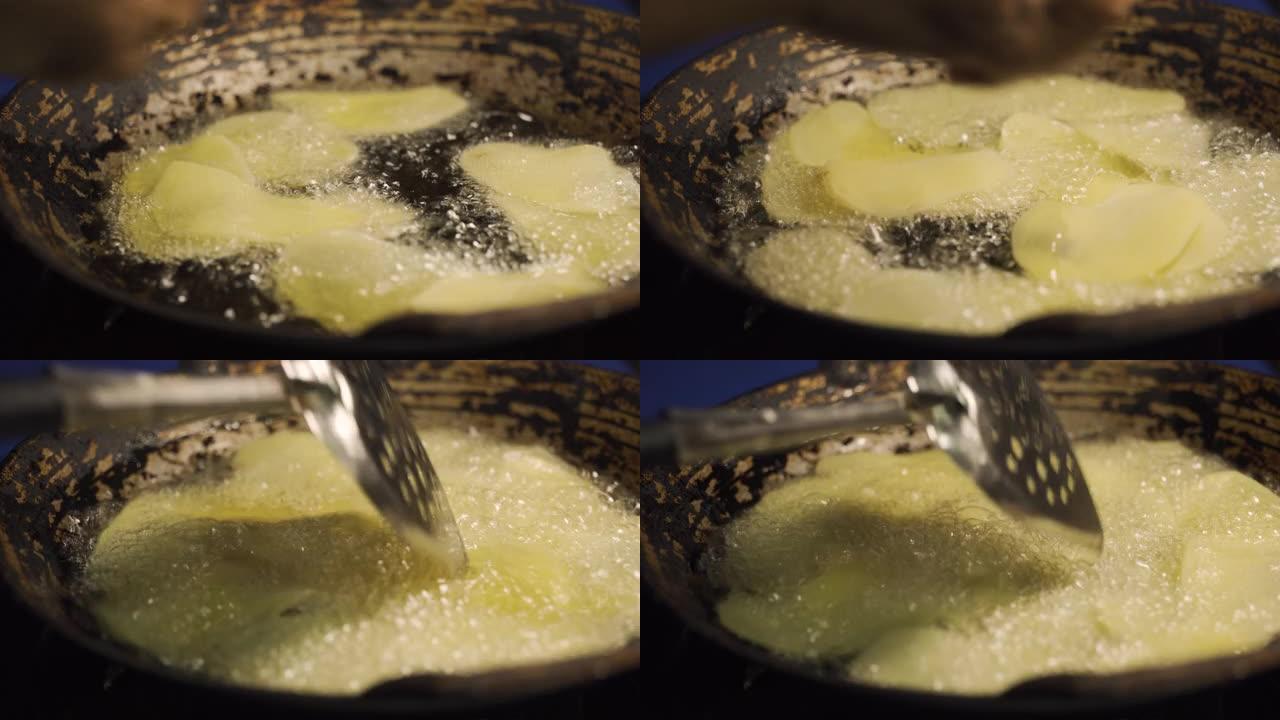 生薯片在装满沸腾油的平底锅上油炸。特写镜头。充满脂肪。对健康有害。自制快餐菜单。