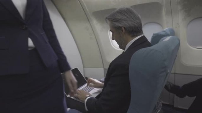 飞机商务舱客舱，乘客坐在座位上。