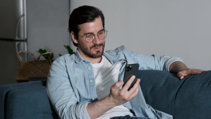 用智能手机与朋友进行在线通话时，一个戴着眼镜的男人微笑着的特写镜头