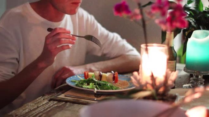 烛光拍摄的朋友吃健康的植物性晚餐的特写镜头。