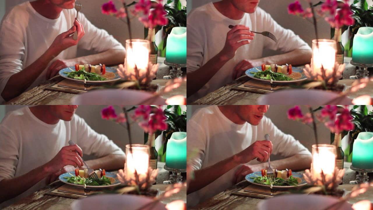 烛光拍摄的朋友吃健康的植物性晚餐的特写镜头。