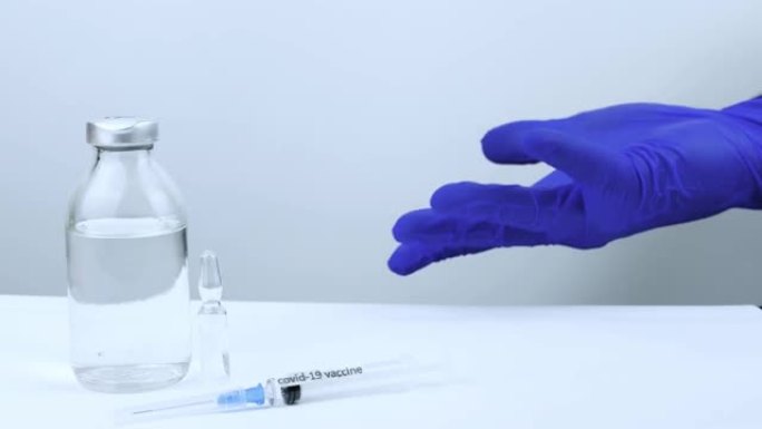 医生演示了针对新型冠状病毒肺炎的疫苗，挥舞着他的手，用疫苗将手指指向瓶子，close-up.The带
