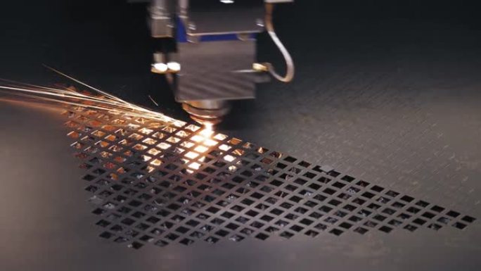 钣金激光切割机。特写。现代数控光纤激光器机器正在金属板上切割图案。切割过程中，明亮的燃烧火花从激光束
