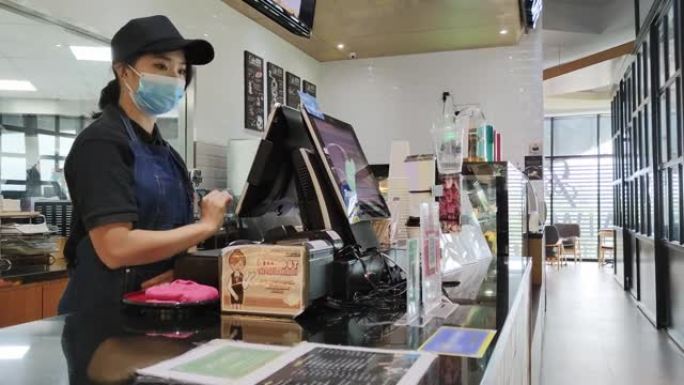 亚洲华人女收银员在酒吧柜台使用触摸屏电脑