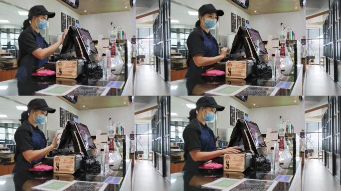 亚洲华人女收银员在酒吧柜台使用触摸屏电脑