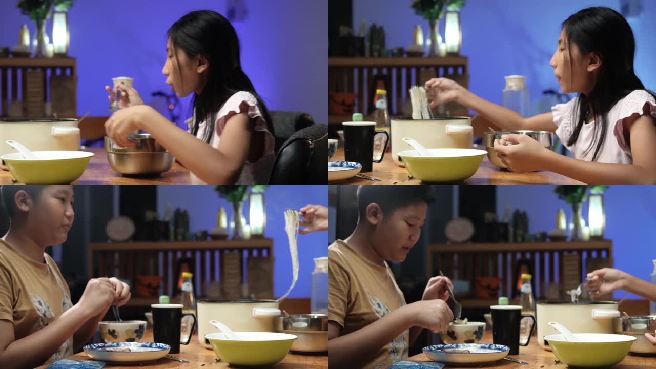 快乐的亚洲儿童晚上在家一起吃火锅sha锅或Sukiyaki，带led灯，生活理念。