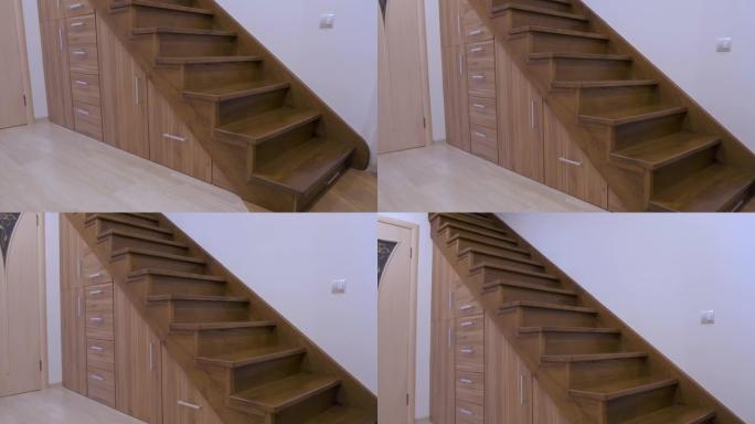 现代建筑内部，豪华走廊，多层住宅中有光滑的木制楼梯。定制的拉出式橱柜在楼梯下的插槽中滑行。使用空间进