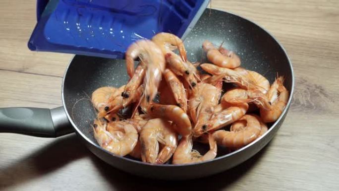 男人把虾放在平底锅上。美味的大虾菜，海鲜，健康食品。维生素和蛋白质。