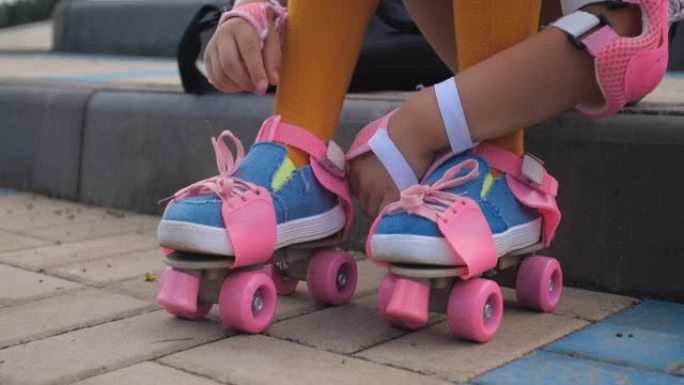 一个小女孩第一次来到轮滑公园学习轮滑。一个穿着粉色旱冰鞋的学龄前漂亮孩子的特写脚，4k慢动作50 F