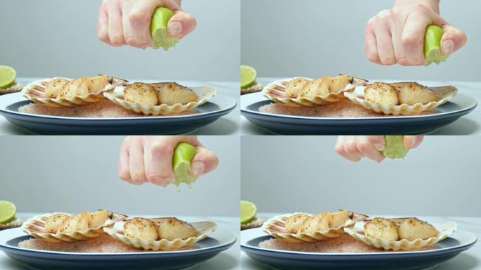 将新鲜油炸的扇贝上的酸橙汁压入盘子中的壳中。厨师女人的手通过慢动作从半个石灰中榨汁来调味海鲜的概念。