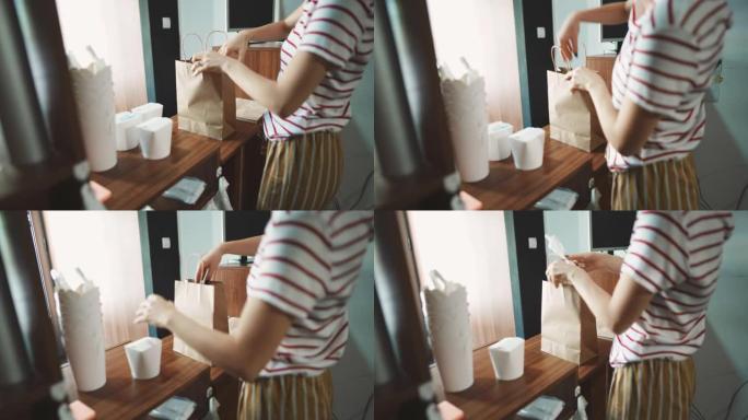 一个无法识别的女性快餐店工人用新鲜的饭菜包装袋子