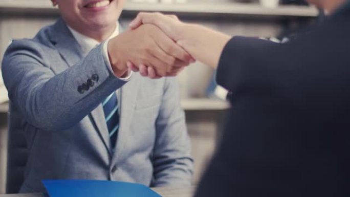 亚洲商人在办公室里站在室内的时候握手合作交易业务，开心自信地接受握手雇主在新工作中被录用。
