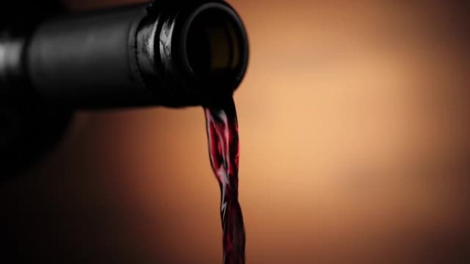 豪华红酒。手将美味的葡萄酒从酒瓶中倒入棕色背景的酒杯中。玫瑰酒是由美味的红葡萄从瓶中倒入高脚杯制成的