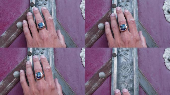 带戒指的手触摸旧纹理坟墓门。传统上男性化的珠宝