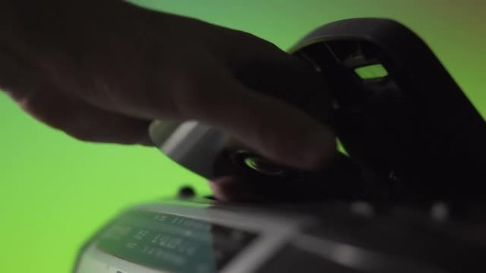 一名男子将激光cd光盘插入绿色背景上的旧音乐播放器中。手靠近。复古技术。上一代音频系统