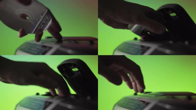 一名男子将激光cd光盘插入绿色背景上的旧音乐播放器中。手靠近。复古技术。上一代音频系统
