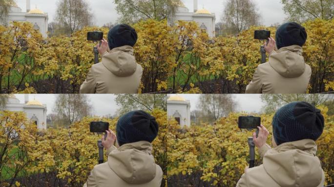 公园里用手机摄像头稳定器录制视频博客的视频记录器男孩