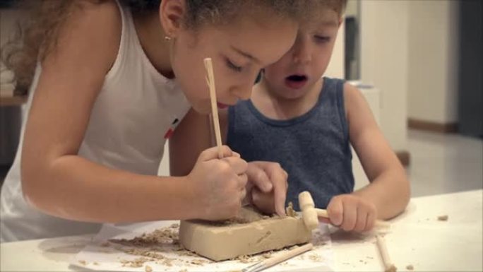孩子们的手，孩子们的特写镜头从一块粘土中扮演多古学家，挖掘出恐龙的儿童教育圈进行绘画和建模。4-9岁