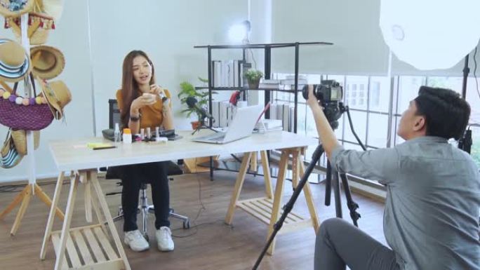 年轻的亚洲夫妇博主录制vlog视频，有影响力的人在工作室用化妆化妆品在社交媒体上直播，在线学习教程