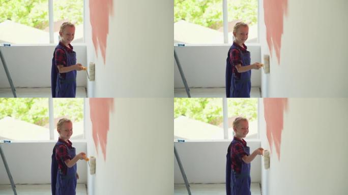 欧洲样貌的男孩用滚筒粉刷房子的墙壁。穿着工作服