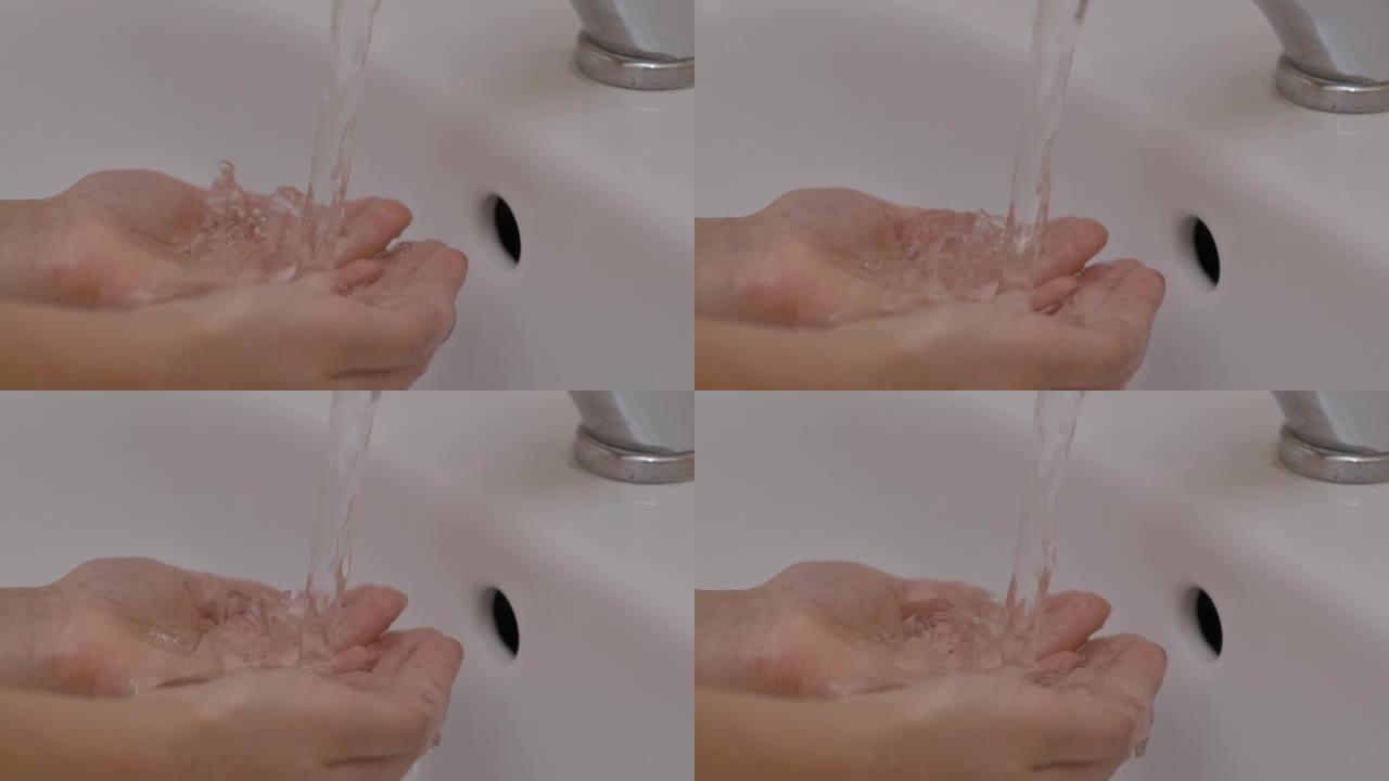 慢动作。人类手在自来水中的纯水流下的特写镜头。儿童手掌在水流下慢动作。家里浴室里的小女孩触摸自来水检