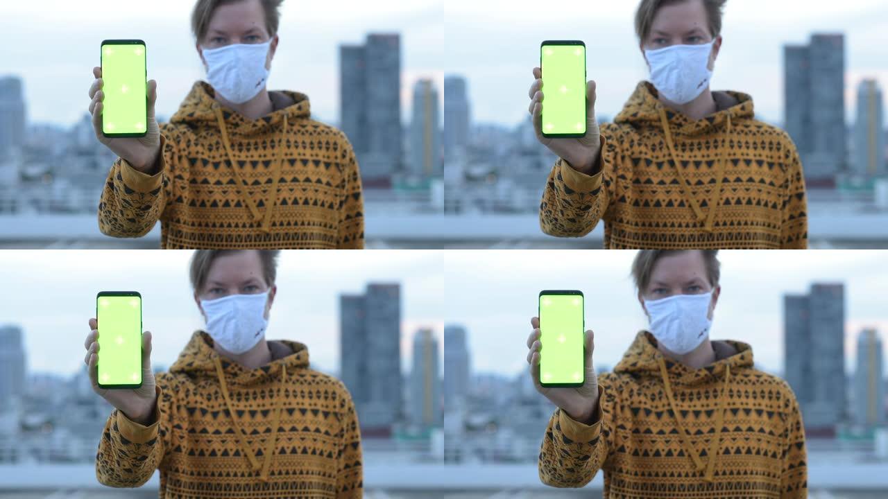 戴着面具的年轻人的脸在城市的视野中显示手机