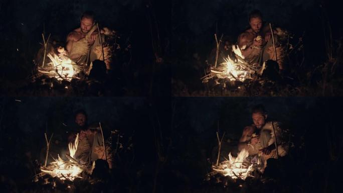 穿着羊皮的原始狩猎采集者坐在地上，在燃烧的火光下吃饭。