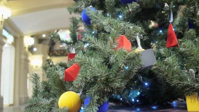 装饰着明亮几何玩具的圣诞树矗立在口香糖购物中心的过道上。访客经过焦点转移