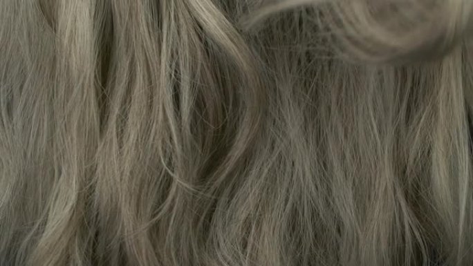 美丽的金色灰色长光滑卷发纹理背景的慢动作。